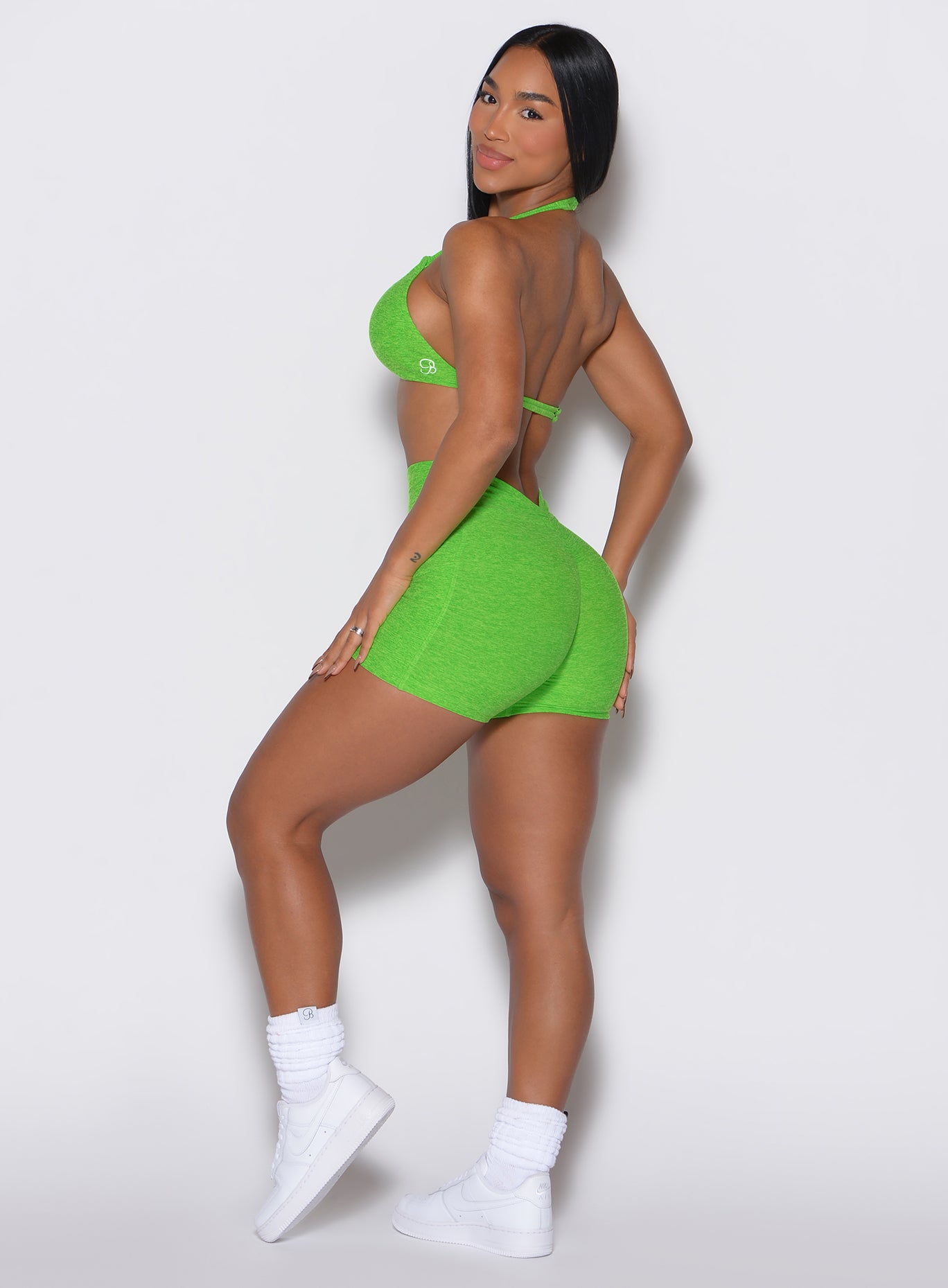 left side profile view of a model wearing our V back shorts in Neon Lime Green color along with the matching bra