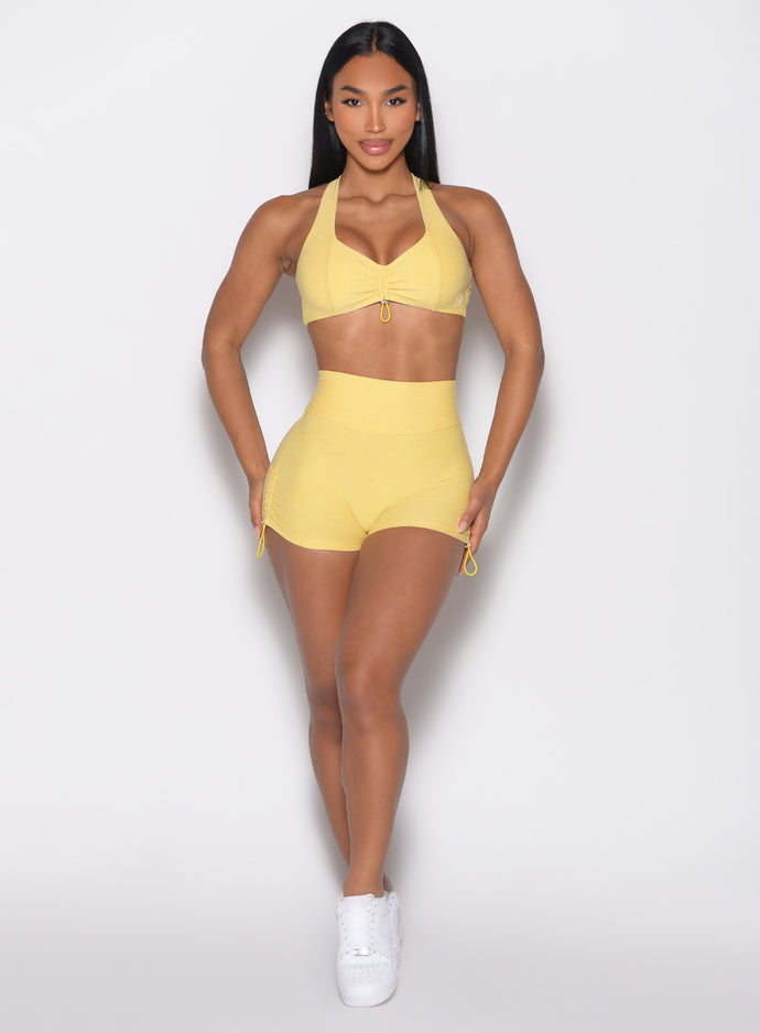 front profile view of a model with both hands on her thighs wearing the V back toggle shorts in Lemon color