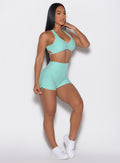 front right side profile view of a model wearing the V back toggle shorts in Oasis color