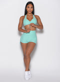front profile view of a model holding the front toggle on the top wearing the V back toggle shorts in Oasis color