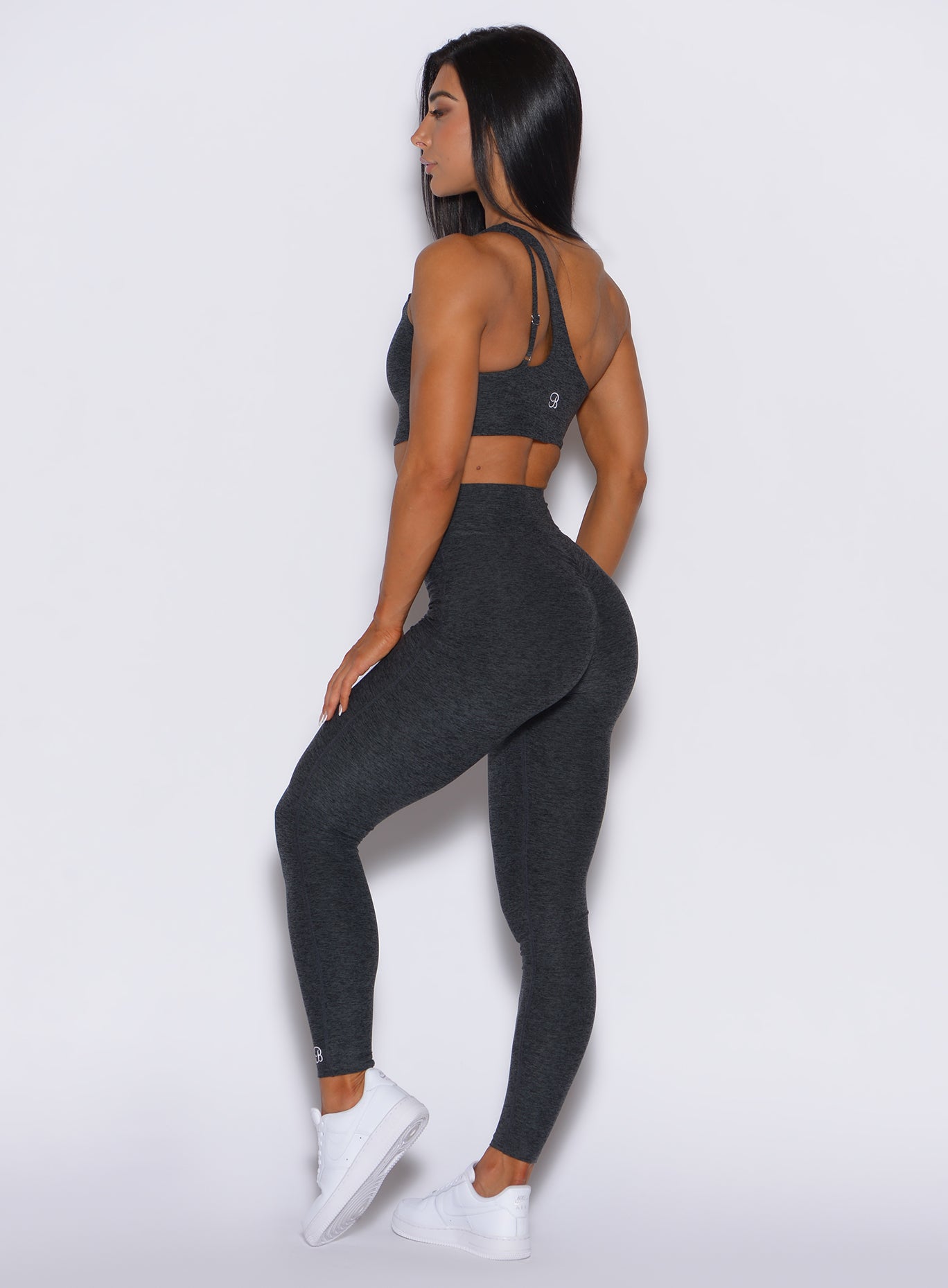 left side profile view of a model wearing our v active leggings in charcoal color along with the matching high rise bottom 
