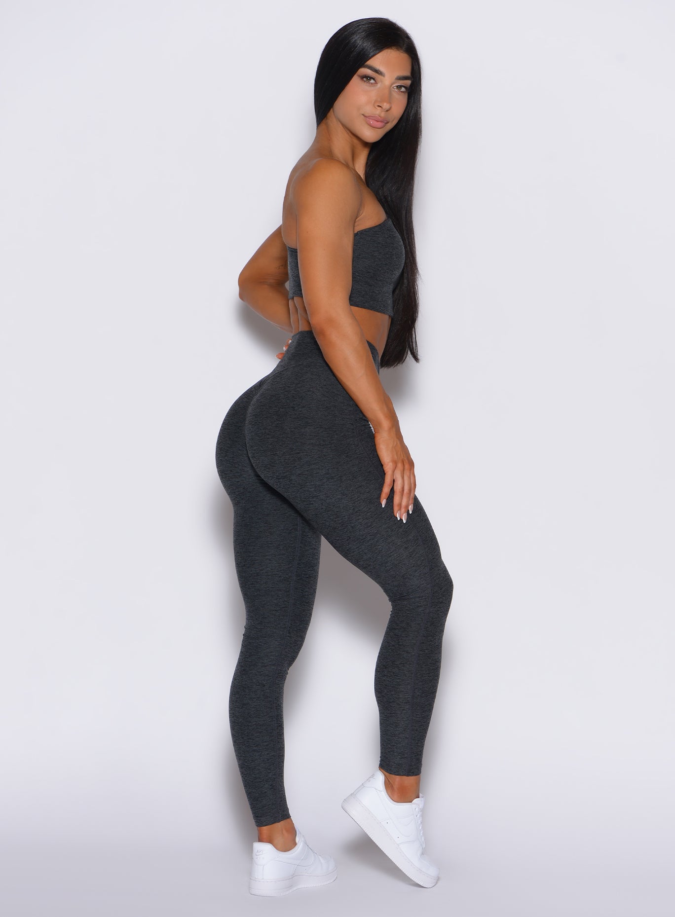 right side profile view of a model facing to her right wearing our V Active Leggings in charcoal color along with the matching top