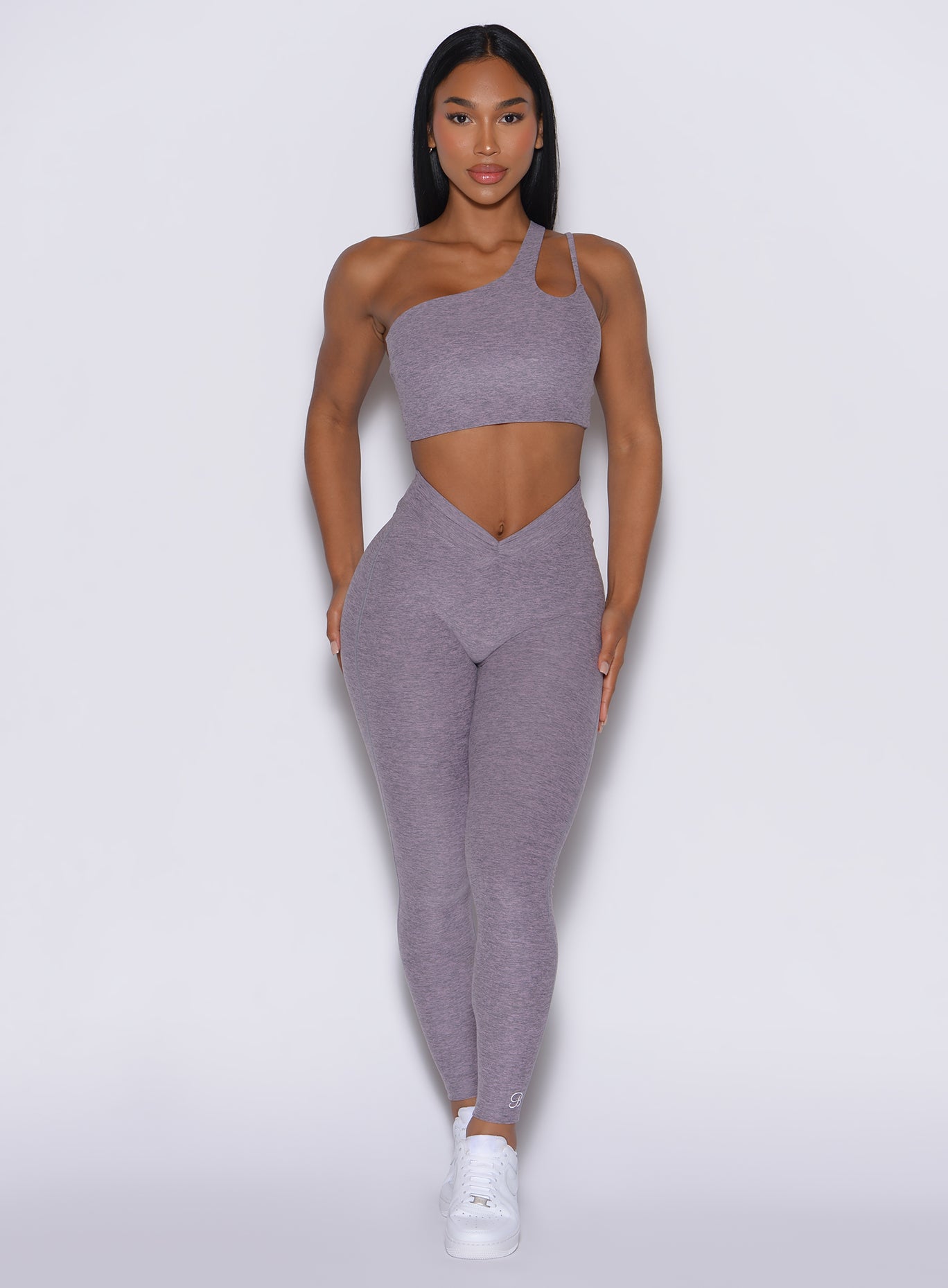 front profile view of a model wearing our V Active Leggings in lilac gray color along with the matching top