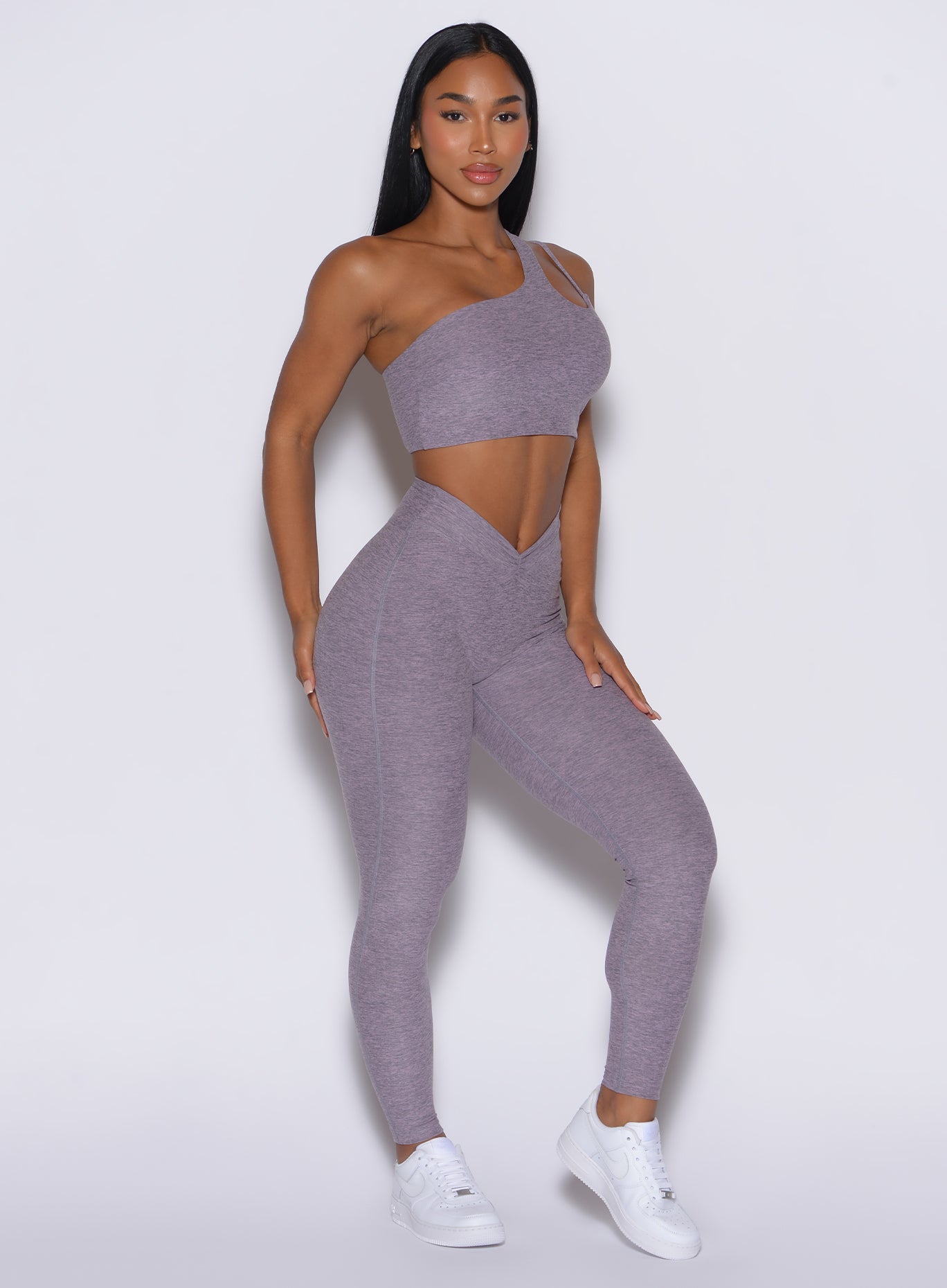 right side profile view of a model angled right wearing our V Active Leggings in lilac gray color along with the matching top