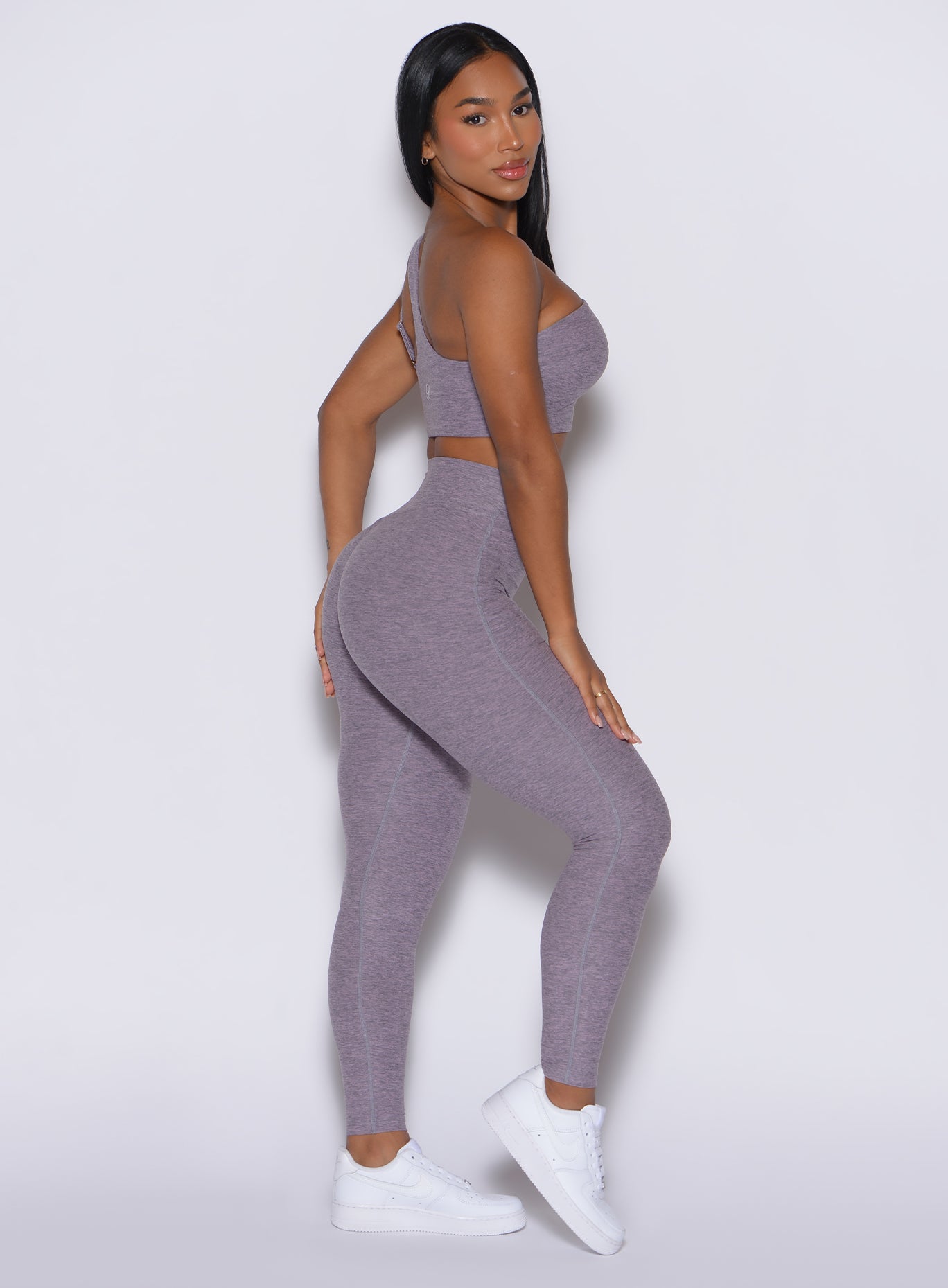 right side profile view of a model wearing our V Active Leggings in lilac gray color along with the matching top