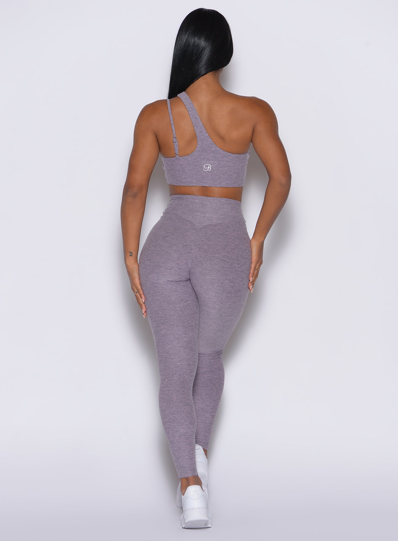 back profile view of a model wearing our V Active Leggings in lilac gray color along with the matching top