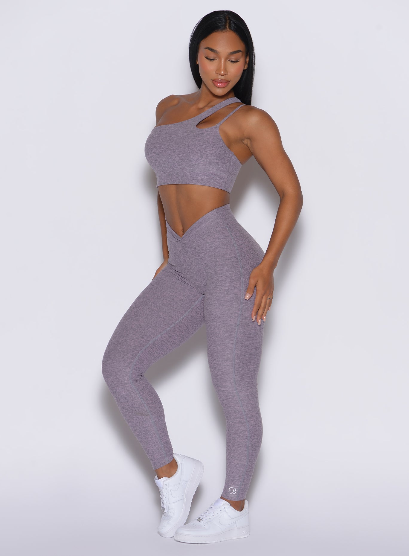 front profile view of a model wearing our V Active Leggings in lilac gray color along with the matching asymmetrical top 