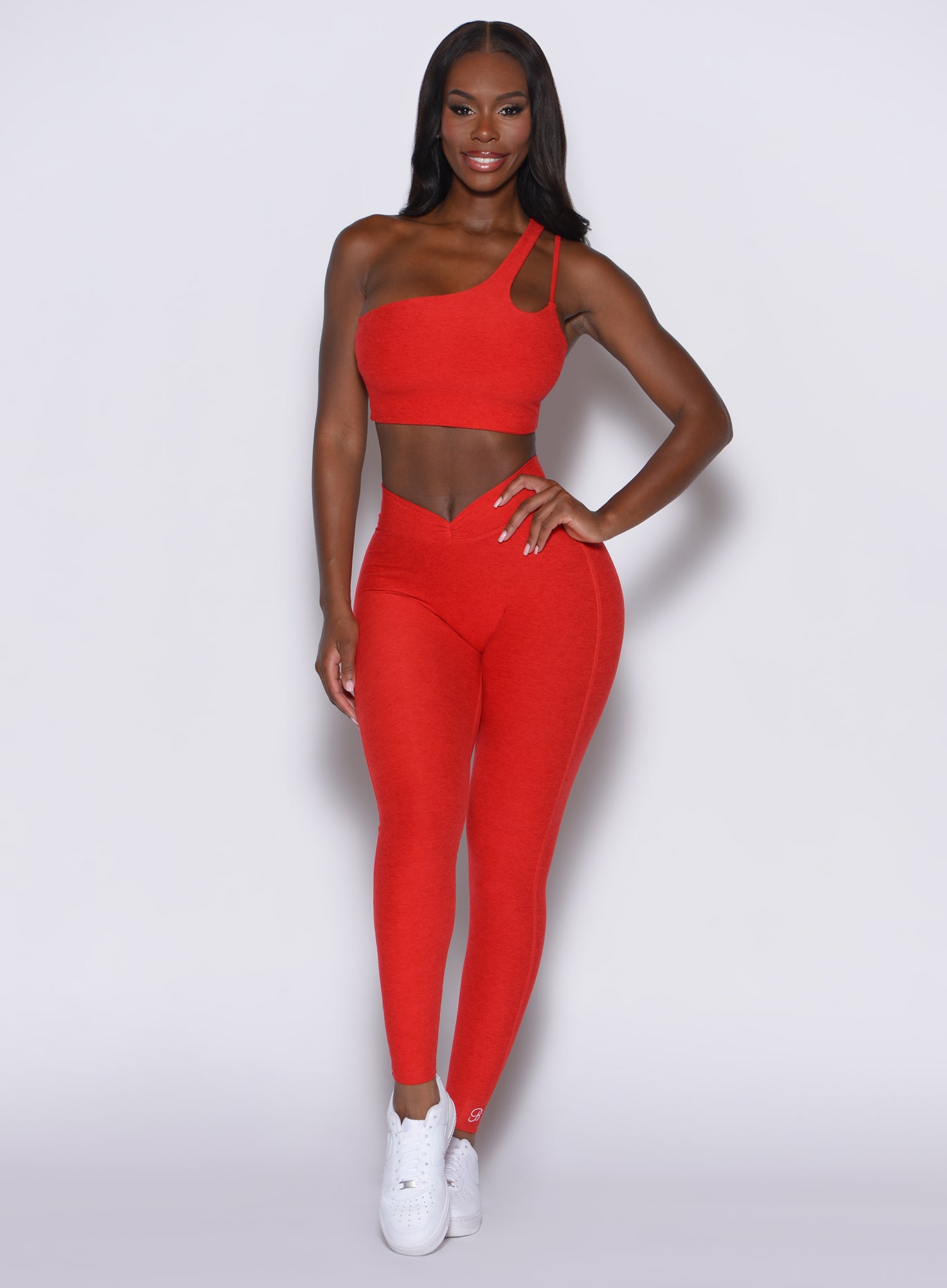 front profile view of a model wearing our V Active Leggings in scarlet red along with the matching top