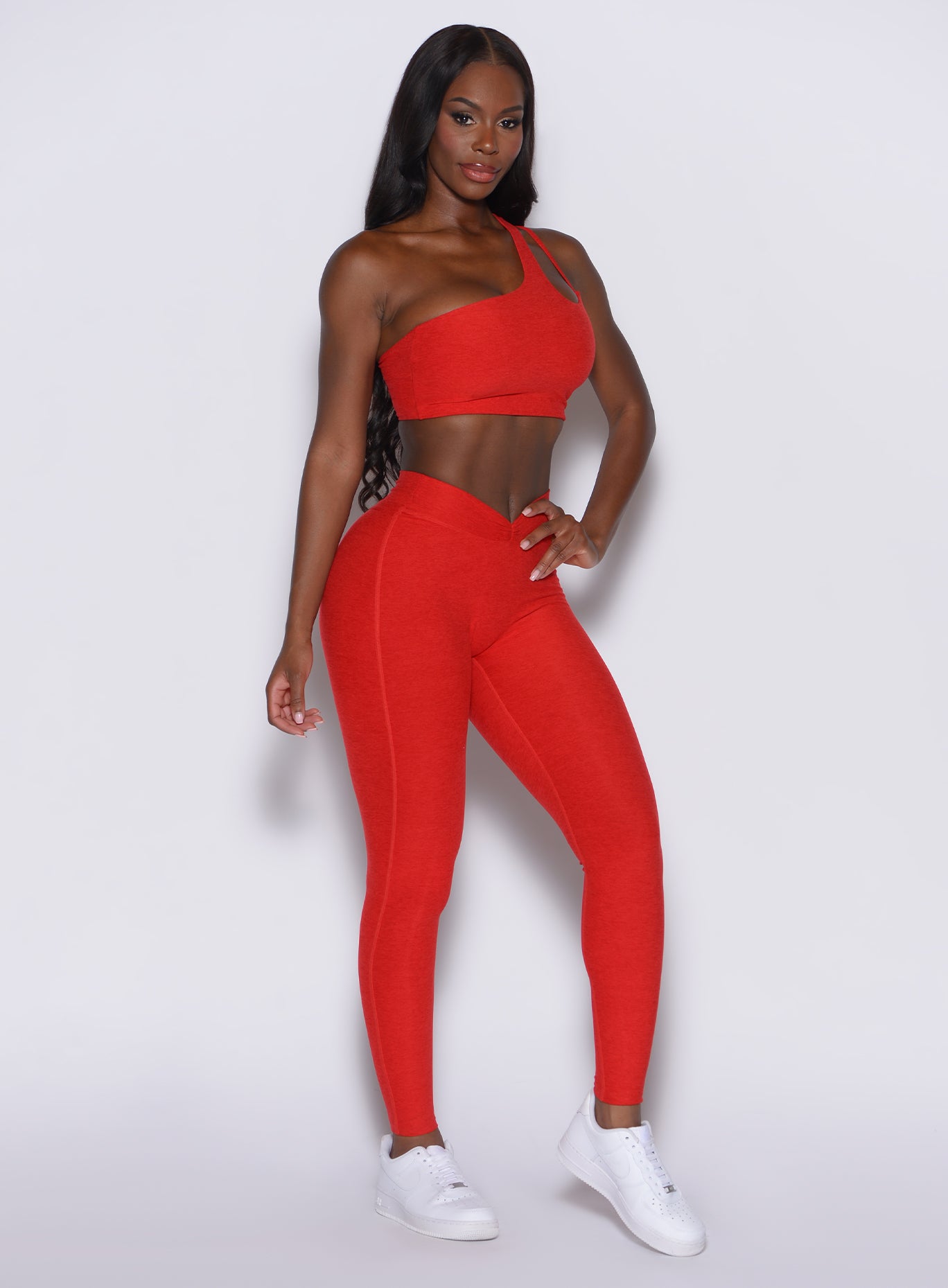 right side profile view of a model angled right wearing our V Active Leggings in scarlet red along with the matching top