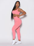 left side profile view of a model facing to her left wearing our v seamless leggings in flamingo color along a matching sports bra