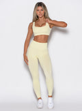 front profile view of a model wearing our v seamless leggings in mellow yellow color along with the matching leggings