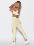 left side profile view of a model facing to her left wearing our v seamless leggings in mellow yellow color along with the matching leggings 