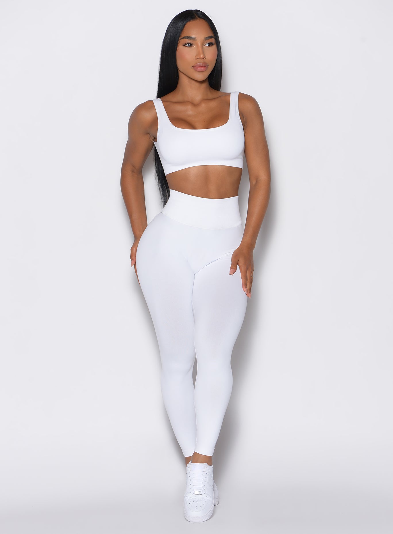 front profile view of a model wearing our white V Seamless Leggings along with a matching sports bra