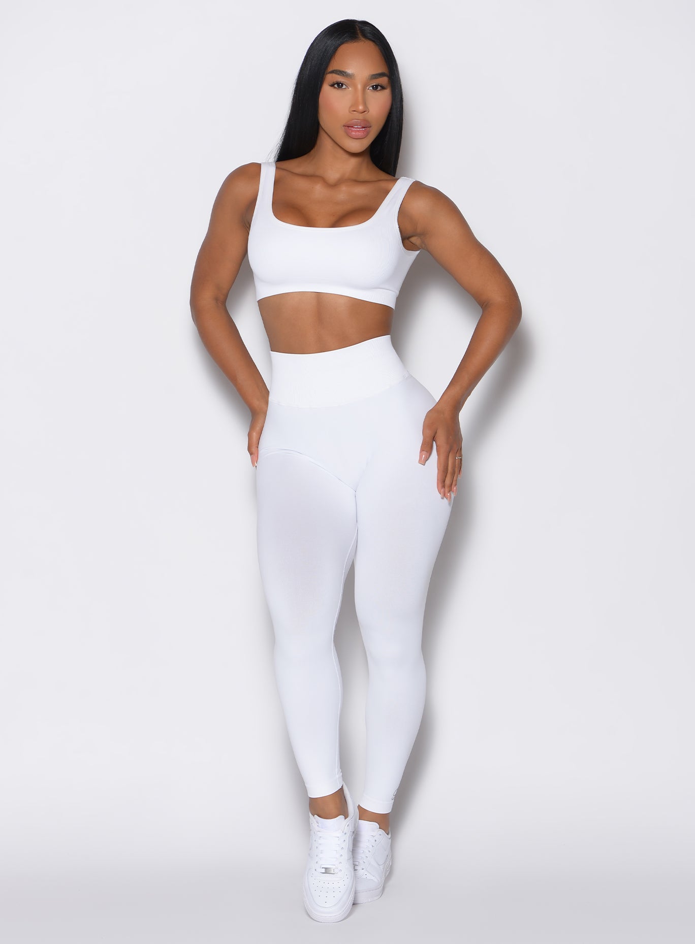 front profile view of a model wearing our white V Seamless Leggings along with a matching bombshell sports bra