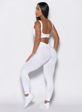 left side profile view of a model wearing our white V Seamless Leggings along with a matching sports bra