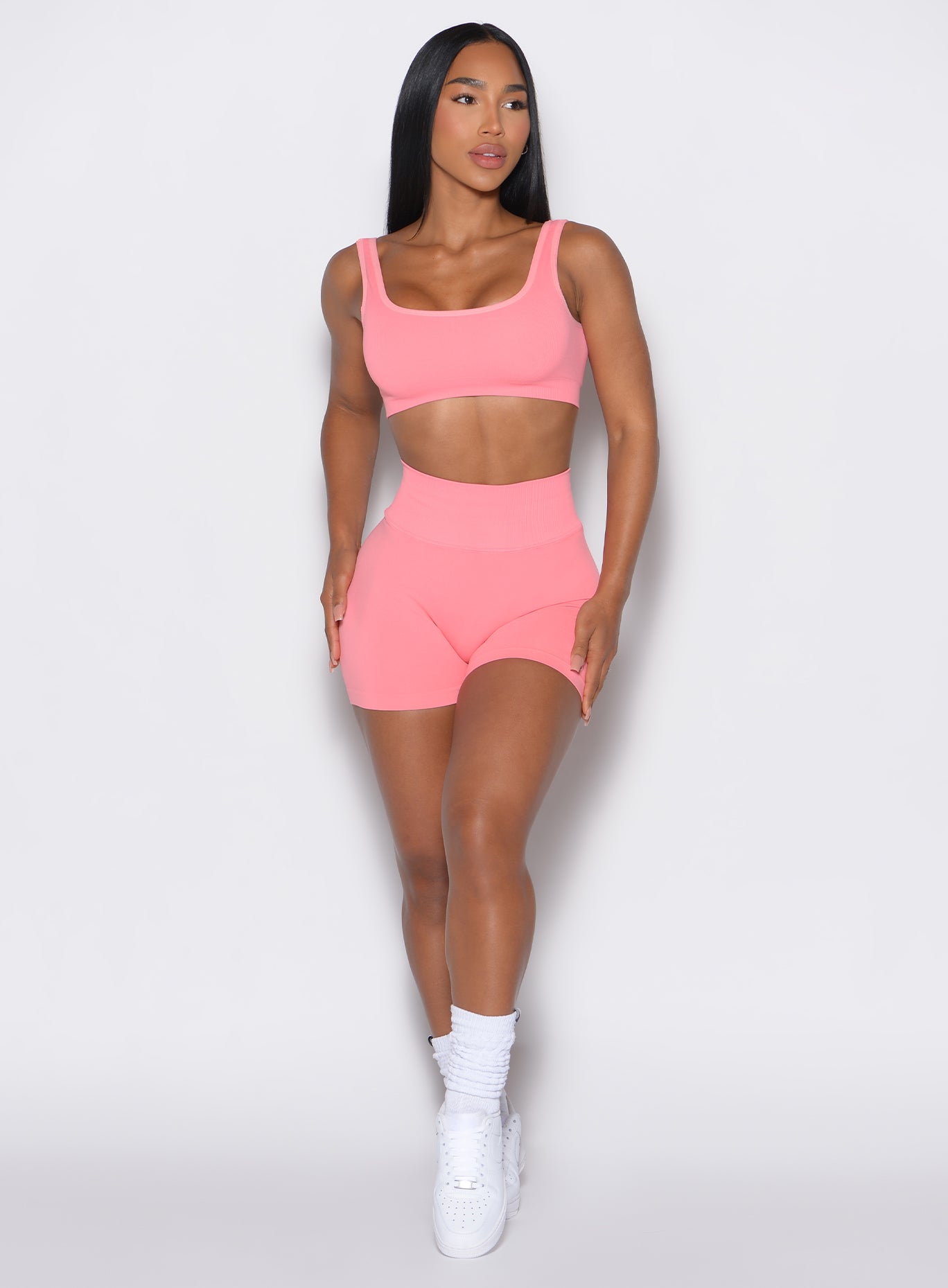 front profile view of a model wearing our white v seamless shorts in flamingo color  along with the matching sports bra
