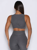Person wearing a gray sleeveless top and high-waisted leggings against a white background