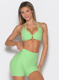 front profile view of a model with one hand on the waistband of the shorts wearing the Voltage sports bra in Electric green color
