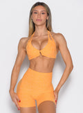 front profile view of a model wearing the Voltage sports bra in Kumquat color 