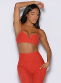 front profile view of a model with one hand resting on top of her head wearing the Wave wire bra in firestorm color