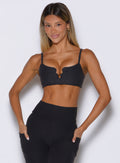 front profile view of a model with both hands inside the side pockets of the leggings wearing the Wave wire bra in heathered black color