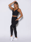 front left side profile view of a model with one hand inside the side pocket wearing the Wave Wire Leggings in Heathered Black color