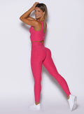 left side view of a model looking over her shoulder wearing the Wave Wire Leggings in pink paradise color