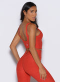 back right side profile view of a model looking over her shoulder wearing the Wave wire tank in firestorm color
