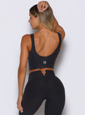 back profile view of a model facing to the left side wearing the Wave wire tank in heathered black color