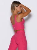 right side profile view of a model wearing the Wave wire tank in pink paradise color