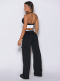Back view of model facing left, wearing Bombshell Sportswear wide leg joggers in Black color with relaxed flowy fit