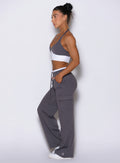 left side profile view of a model wearing Bombshell Sportswear wide-leg cargo lounge pants designed for everyday wear, featuring a soft ‘butter-like’ fabric, adjustable drawcord waistband, flowy flattering fit, and functional side pockets with cargo detailing.