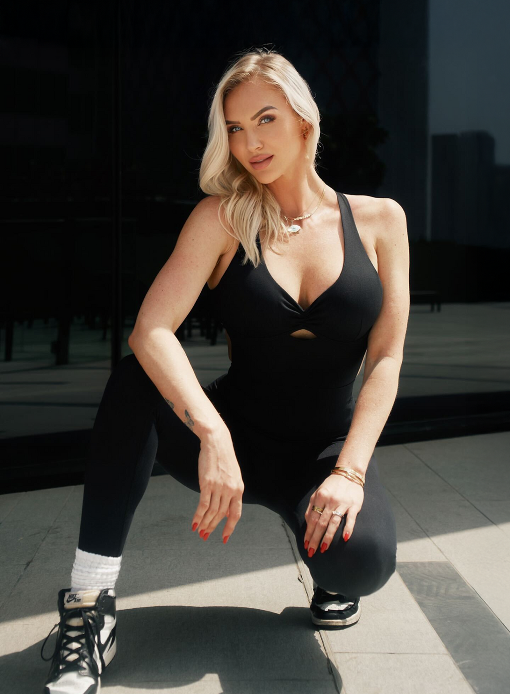 Woman in a black outfit posing outdoors on a sunny day