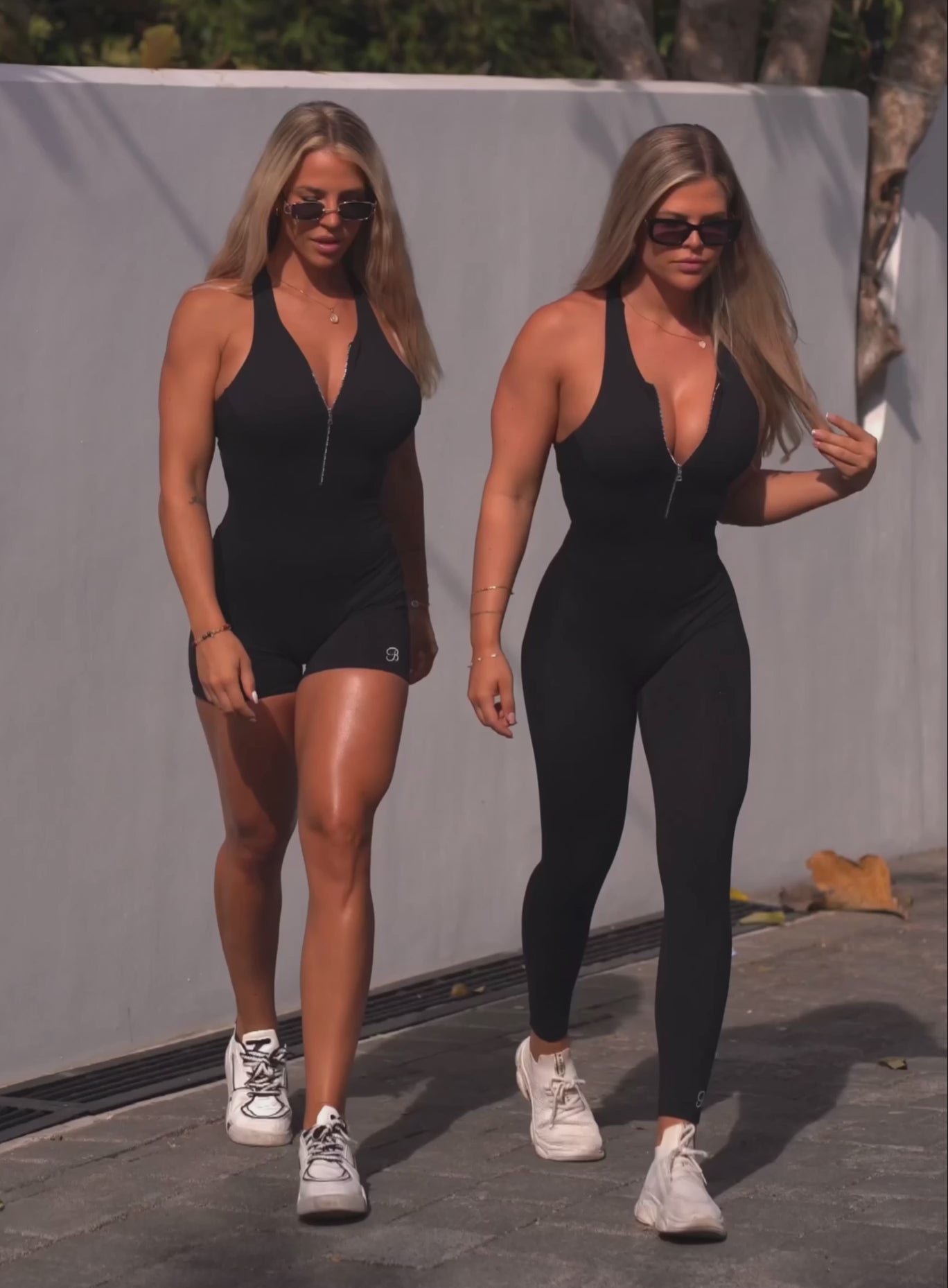 two blondes walking together one is wearing the aip front bodysuit shorts and one is wearing the long legth bodysuit