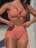 Video of a fit model wearing an orange sports bra with a bow detail and matching athletic shorts.