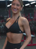 Video of a fit model working out. She's wearing a black sports bra and matching athletic shorts.