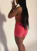 a short video of a model wearing our V back shorts in Neon Apricot Pink color along with the matching sports bra