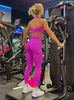 Video of a model at the gym wearing purple athletic set. The set includes a halter sports bra and matching leggings with cargo pockets.
