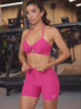 Fit model at the gym wearing matching athletic set. The set includes a strappy sports bra and v waisted shorts with an adjustable waistline.