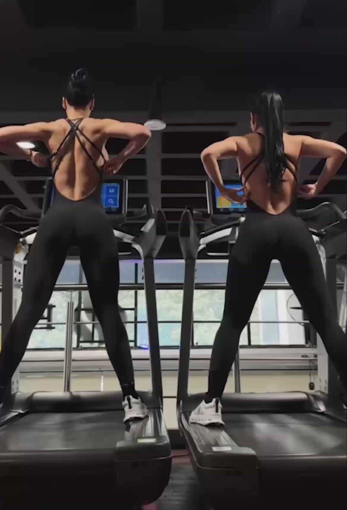 Video of two girls working out in a gym wearing matching black bodysuits.