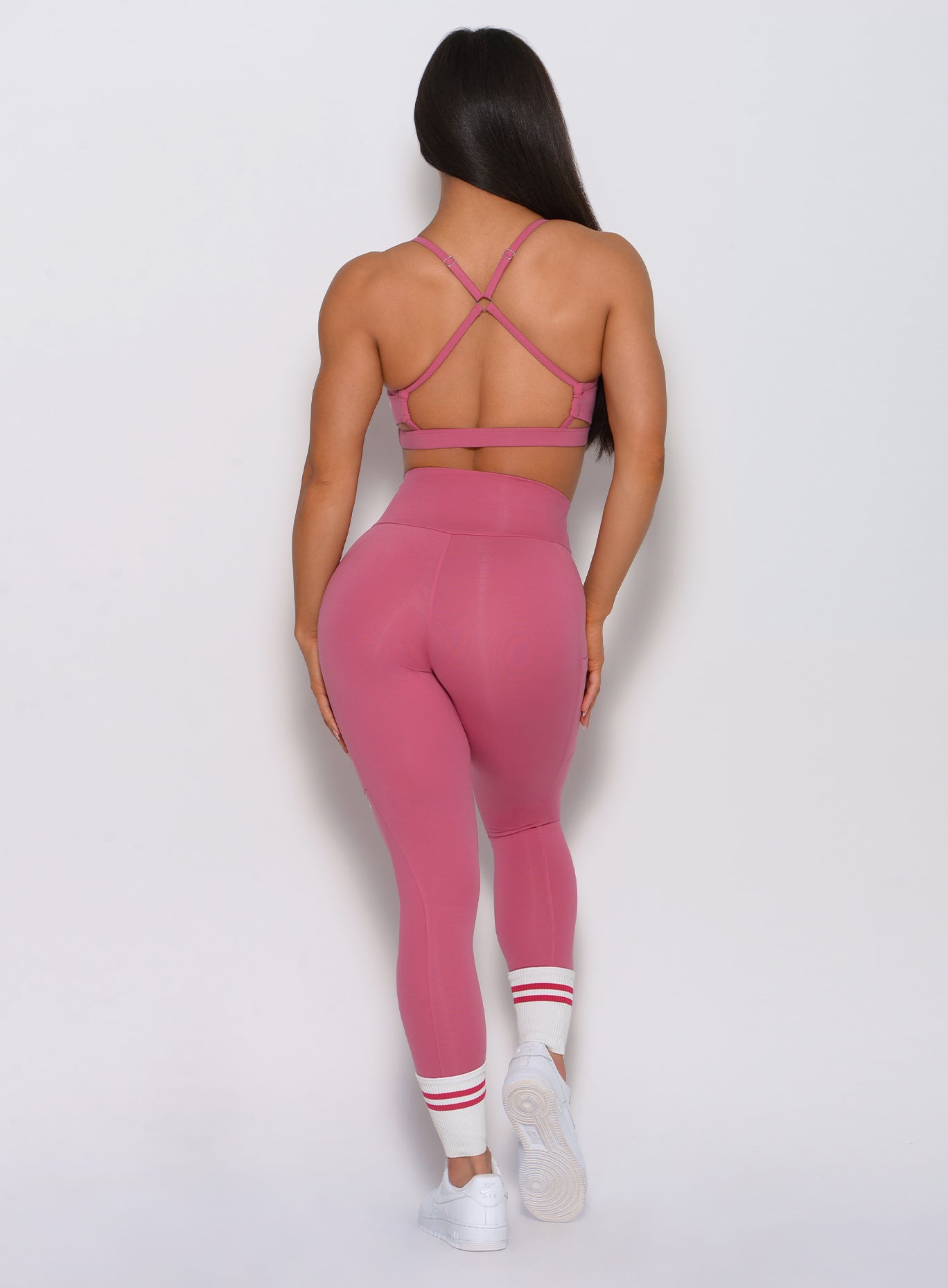 Full back view of the model wearing our pumped sports bra in blush color and a matching high waist leggings