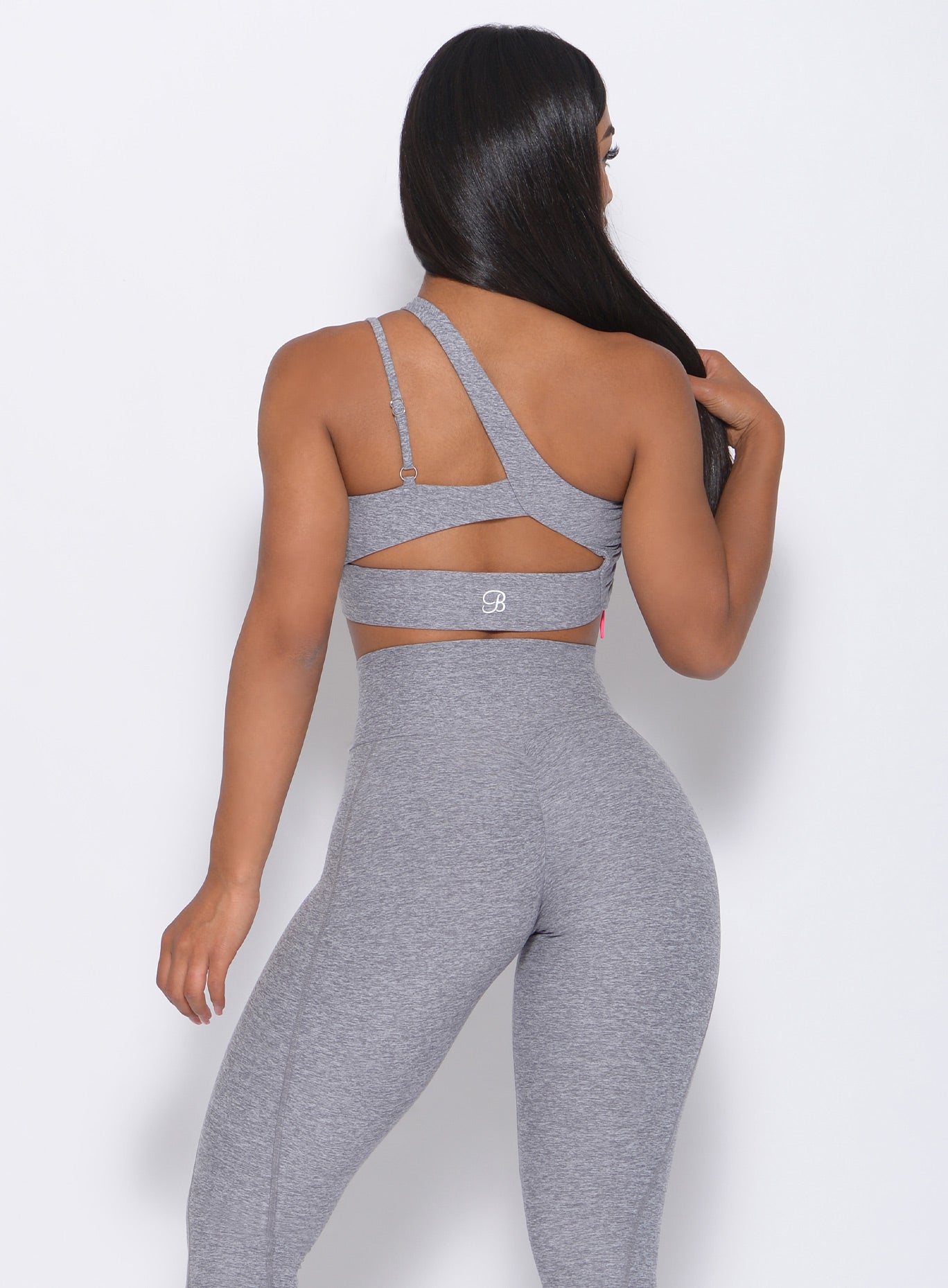 Back view of the model wearing our asymmetrical scrunch bra in cloud color and a matching leggings