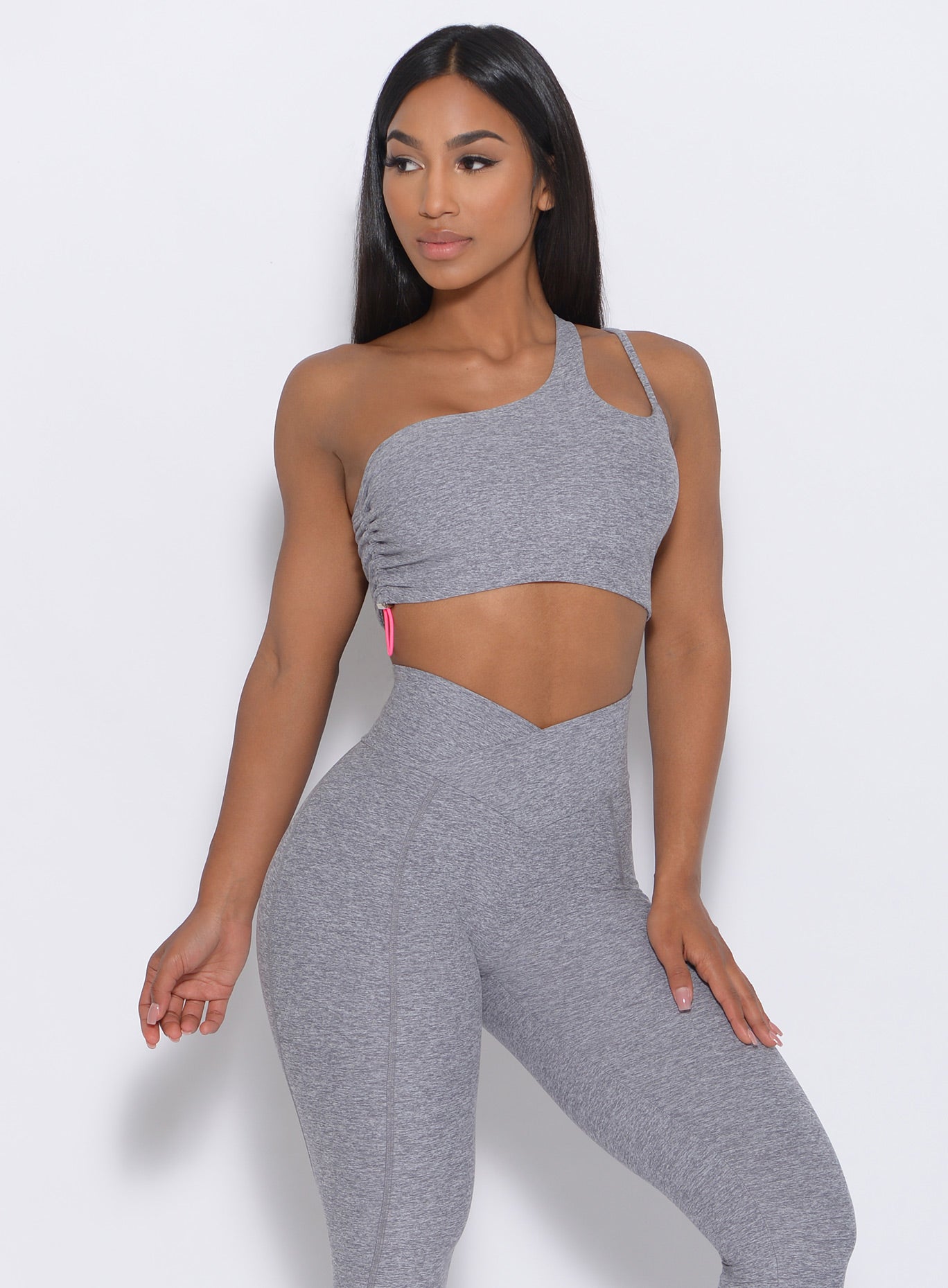 Front profile of the model with her left hand on thigh wearing our asymmetrical scrunch bra in cloud color and a matching leggings