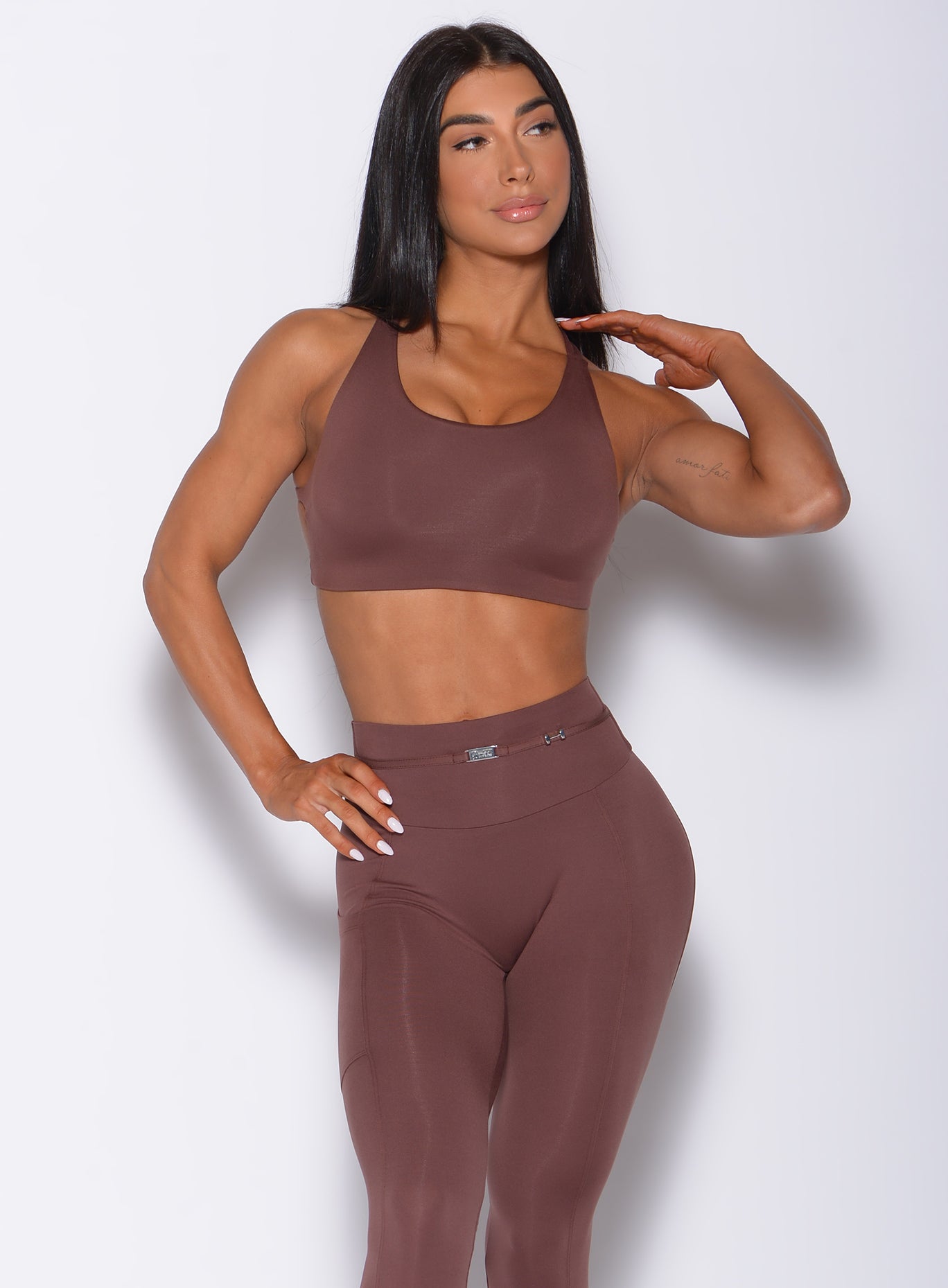 Front profile view of a model wearing our barbell sports bra in chocolate color and a matching leggings