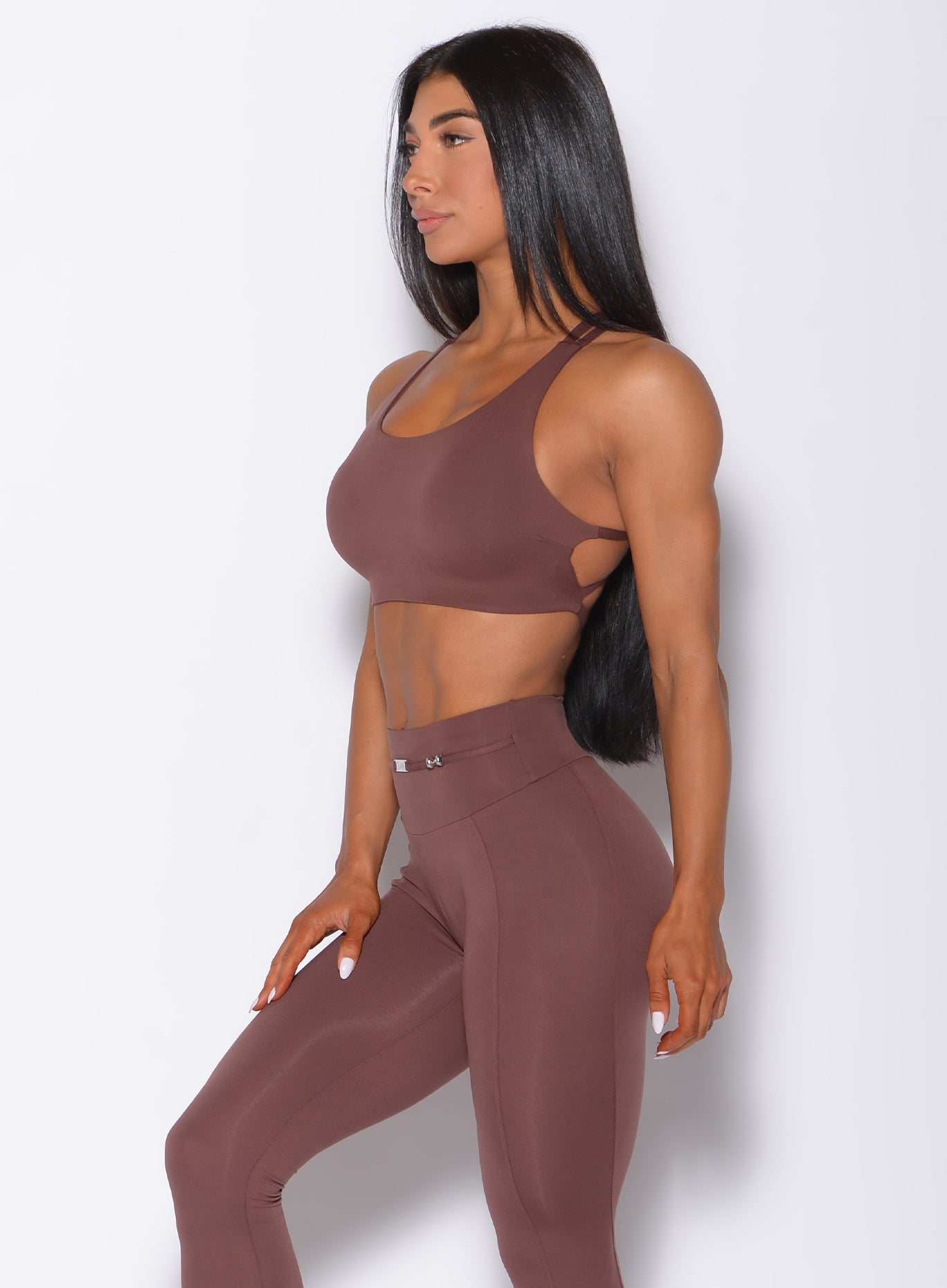 Left side profile view of a model angled left wearing our barbell sports bra in chocolate color and a matching leggings