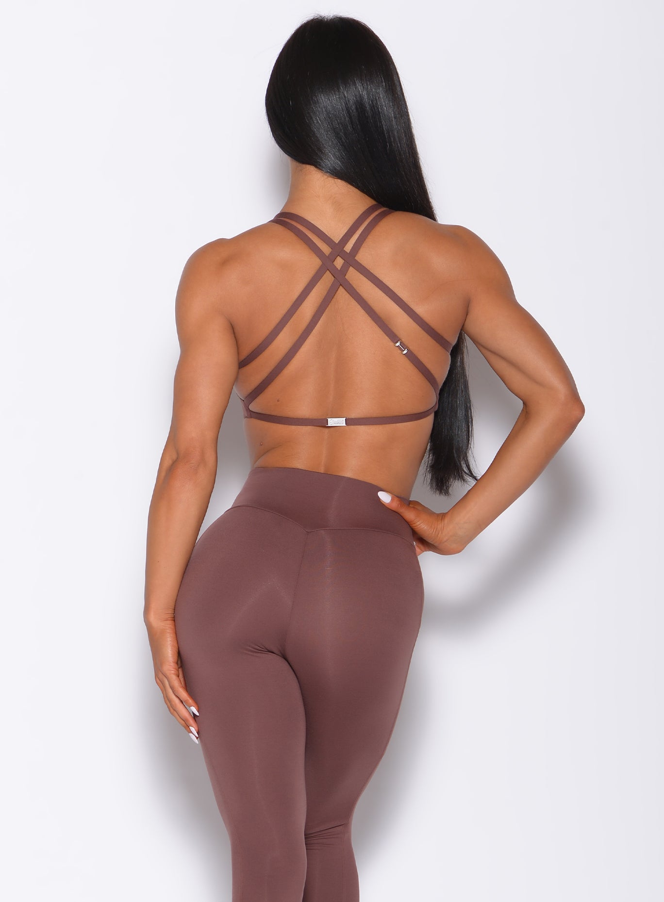 Back profile view of a model in our barbell sports bra in chocolate color and a matching leggings