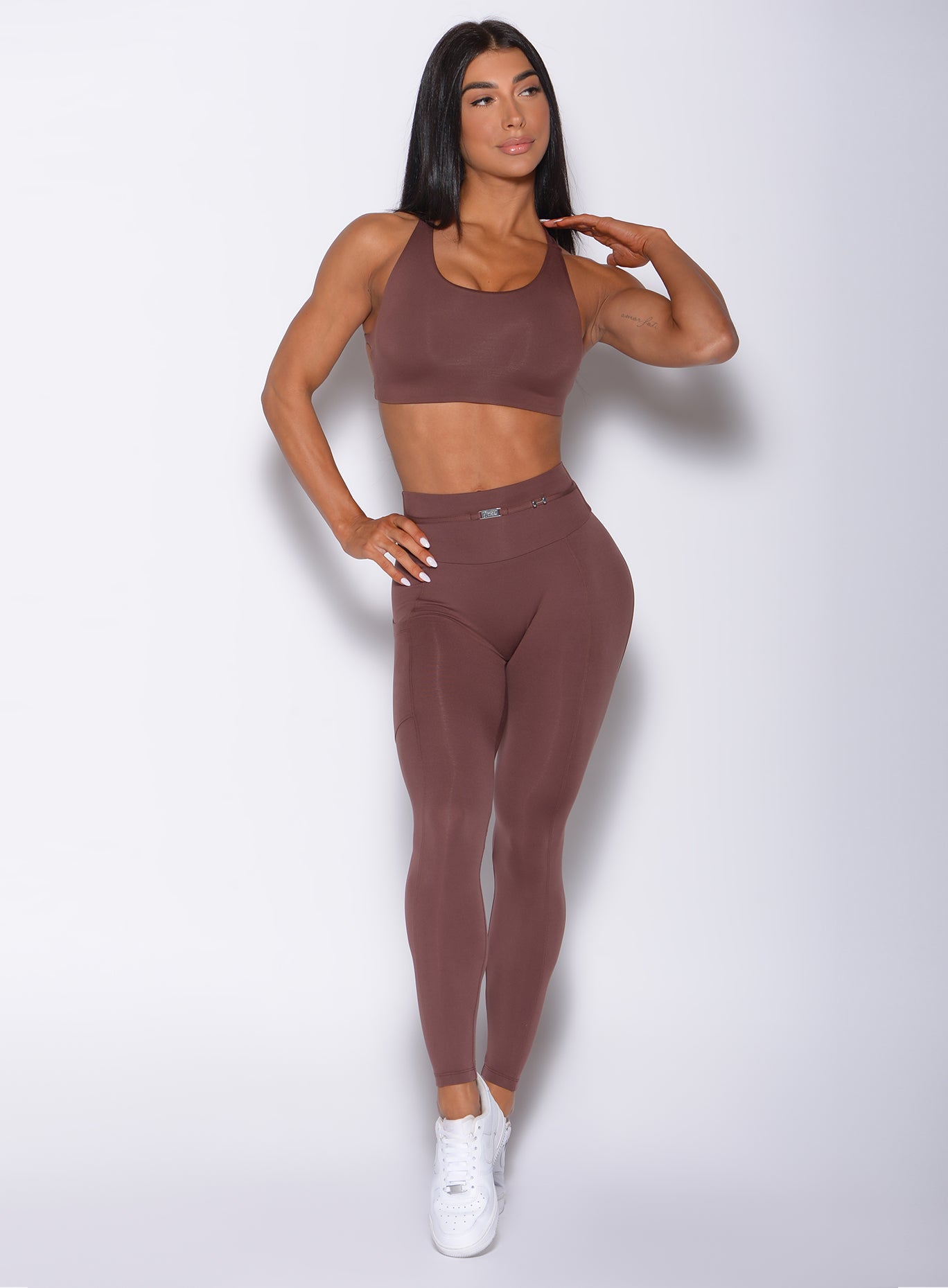 Front profile view of a model wearing our barbell leggings in chocolate color and a matching bra