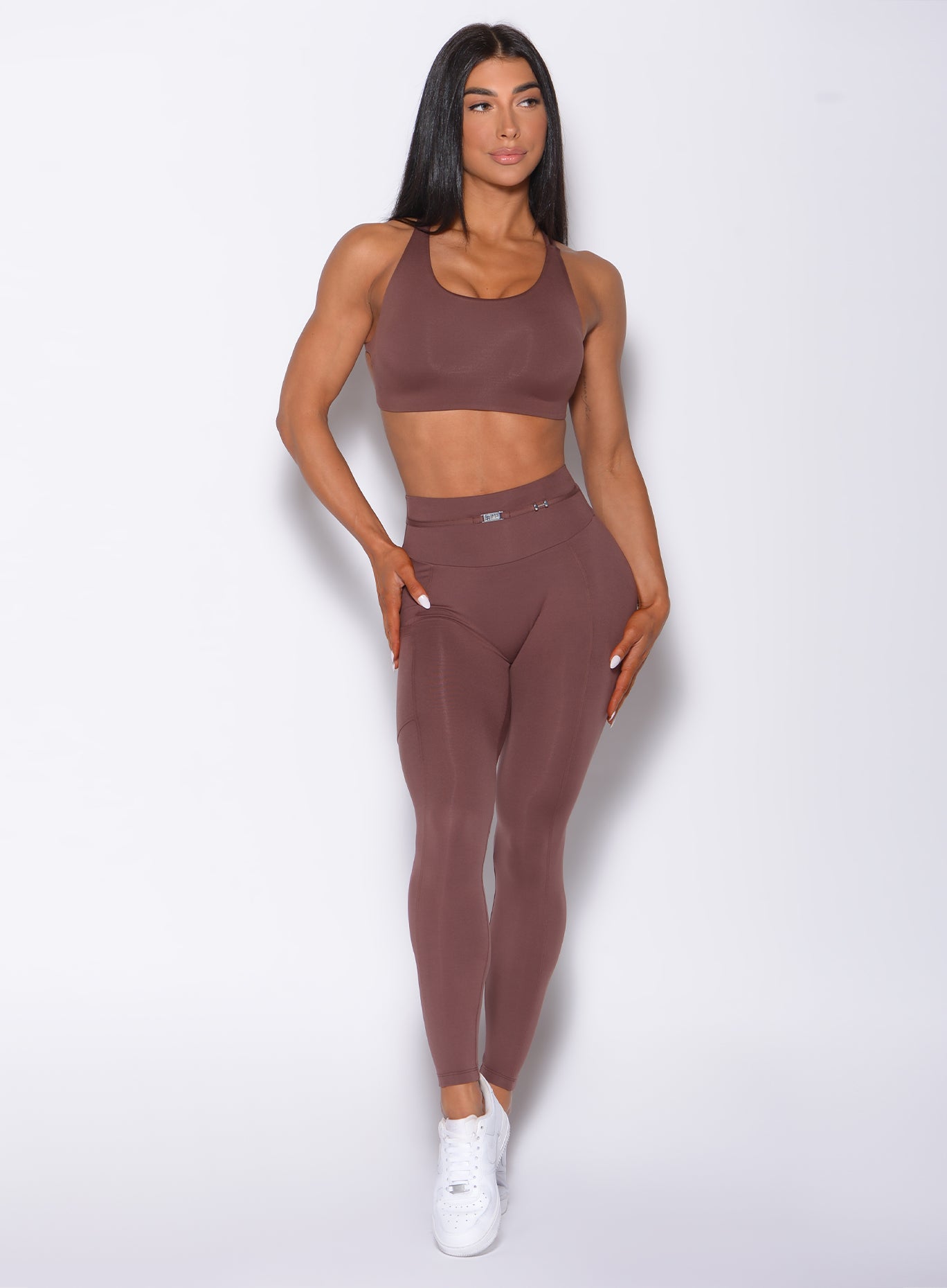 Front profile view of a model in our barbell leggings in chocolate color and a matching bra