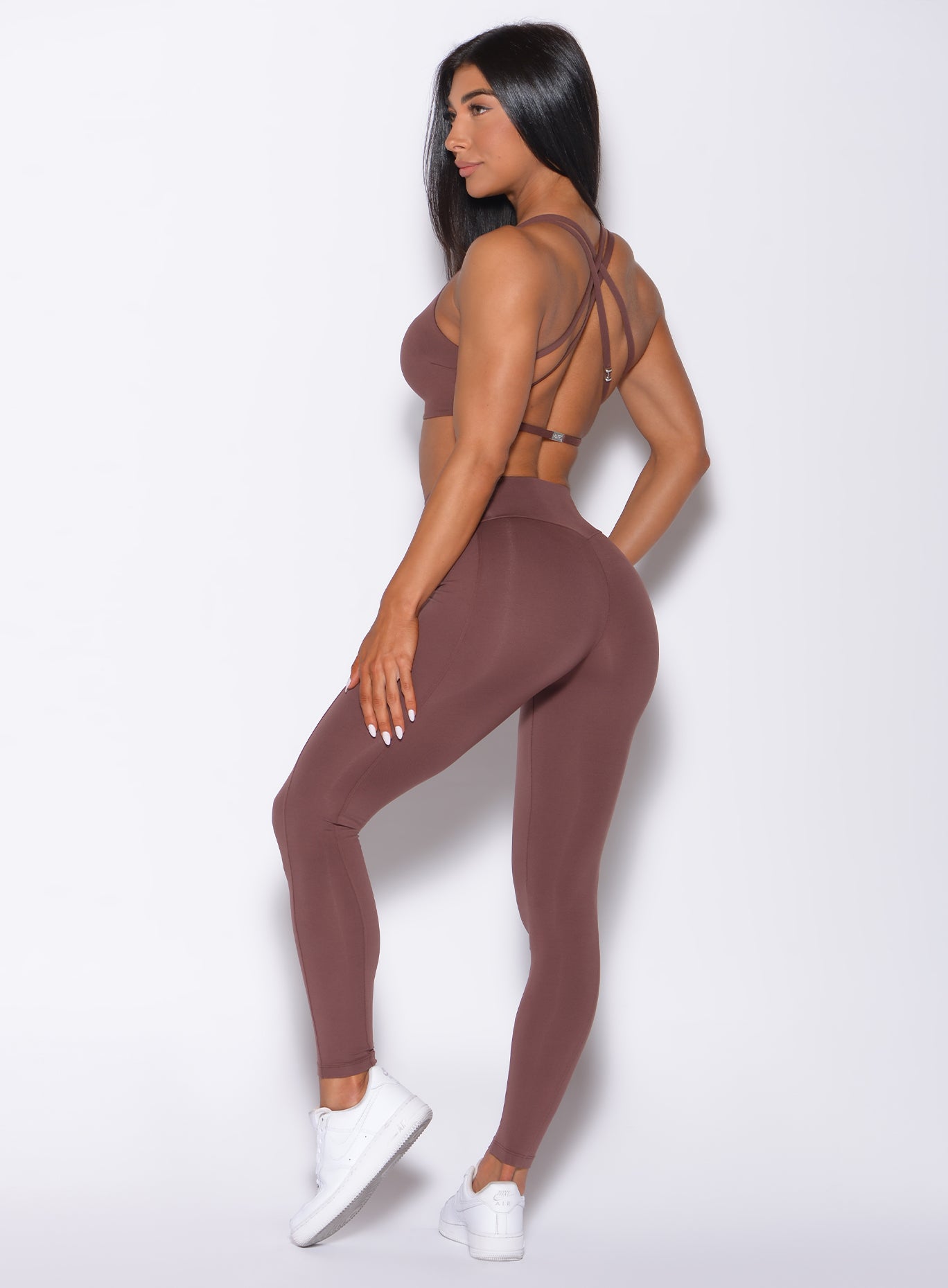 Left side profile view of a model in our barbell leggings in chocolate color and a matching bra