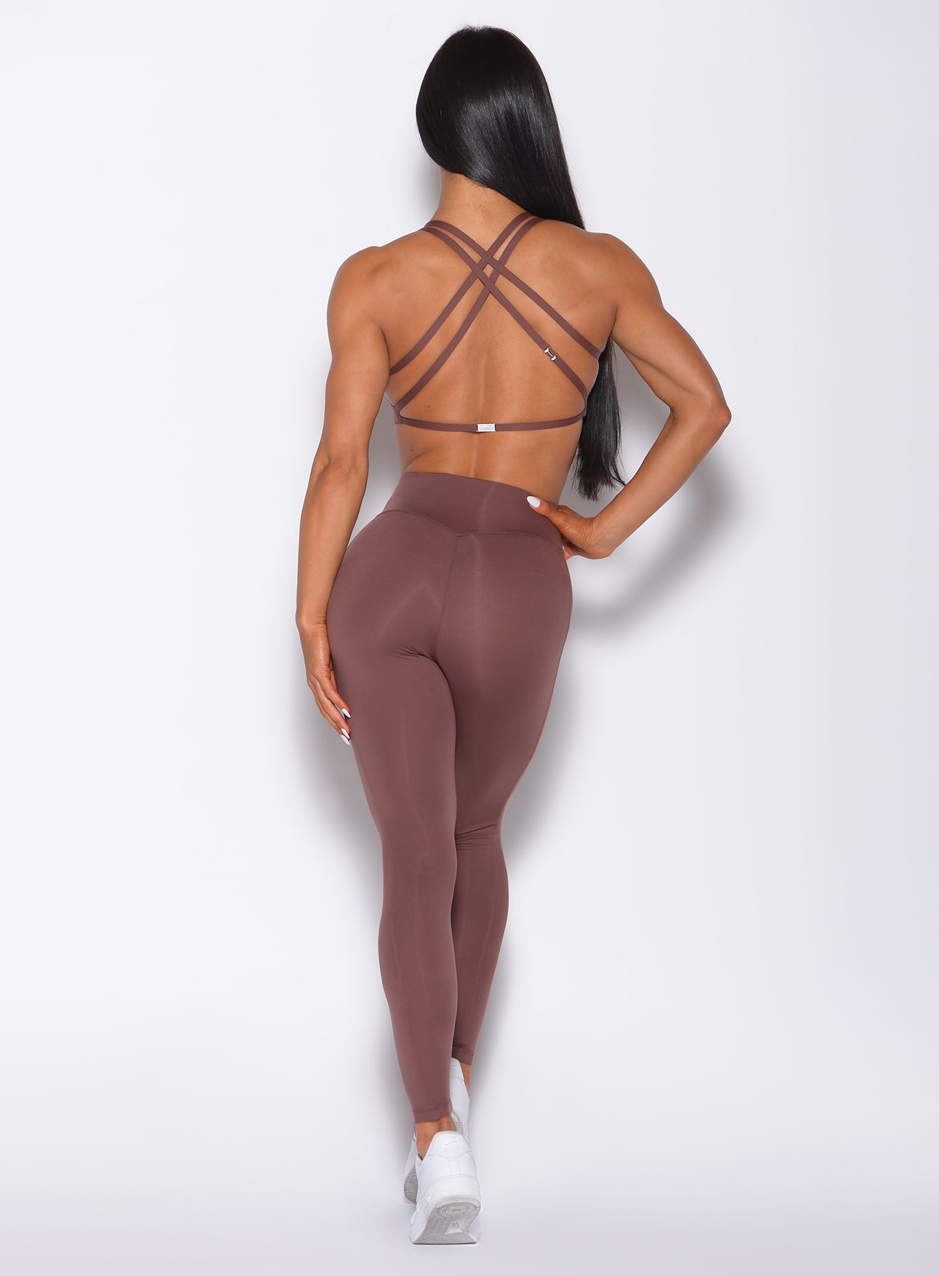 Back profile view of a model in our barbell leggings in chocolate color and a matching bra